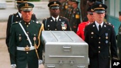 FILE - U.N. honor guards carry a coffin containing the remains of American soldiers after it was returned from North Korea at the border village of Panmunjom, South Korea, May 14, 1999. South Korean media reported that the U.S. military planned to send caskets to North Korea through a border village on June 23, 2018, so that the North could begin the process of returning the remains of U.S. soldiers missing since the 1950-53 Korean War.