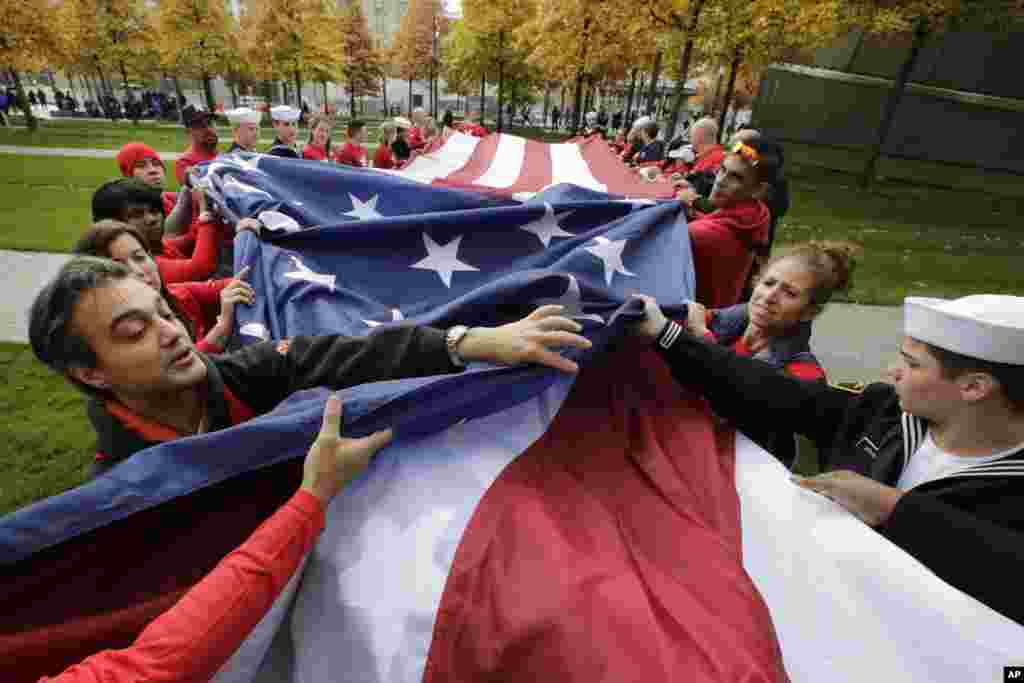Volunteers with the veterans advocacy group Team Red White and Blue unfurl a large American flag at the National September 11 Memorial in New York Sunday. 