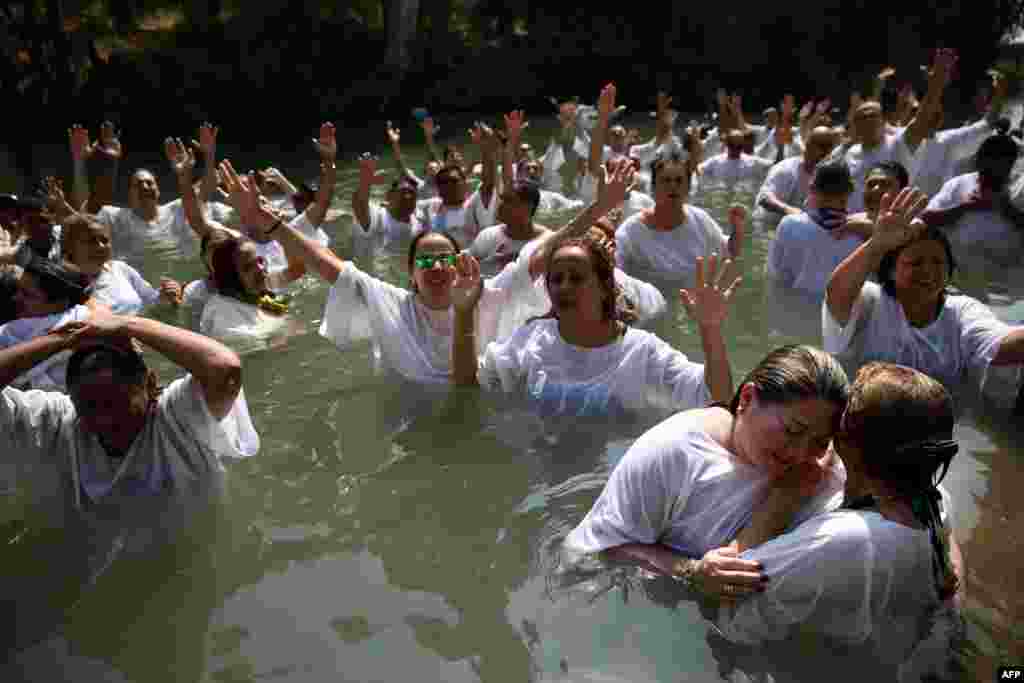Evangelical Christian pilgrims from Brazil raise their hands in the air as they pray during a mass baptism ceremony, in the waters of the Jordan River at Yardenit in northern Israel. According to the gospels Jesus Christ was baptized in the water of the Jordan River by John the Baptist.