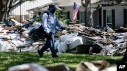 Lonzell Rector, seorang tukang pos, mengantar surat di kawasan permukiman yang penuh puing-puing berserakan di kota Houston, Texas pasca badai Harvey (foto: ilustrasi). Akibat badai Harvey dan Irma diperkirakan banyak warga AS kehilangan pekerjaan. 