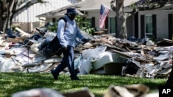 Postal worker Lonzell Rector makes his rounds among flood-damaged debris from homes that lines the street in the aftermath of Hurricane Harvey in Houston, Sept. 7, 2017. 