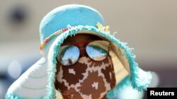 A woman wears a protective face mask during food distribution, as South Africa starts to relax some aspects of a stringent nationwide coronavirus disease (COVID-19) lockdown, in Diepsloot near Johannesburg.