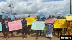 Schoolchildren, their parents and teachers hold a protest after gunmen opened fire at a school, killing at least six children as authorities claim, in Kumba, Cameroon Oct. 25, 2020. 