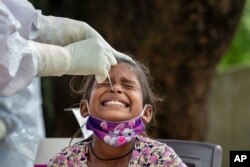An Indian girl cries as a medical worker collects her swab sample for a COVID-19 test at a rural health center in Bagli, outskirts of Dharmsala, India, Sept. 7, 2020.