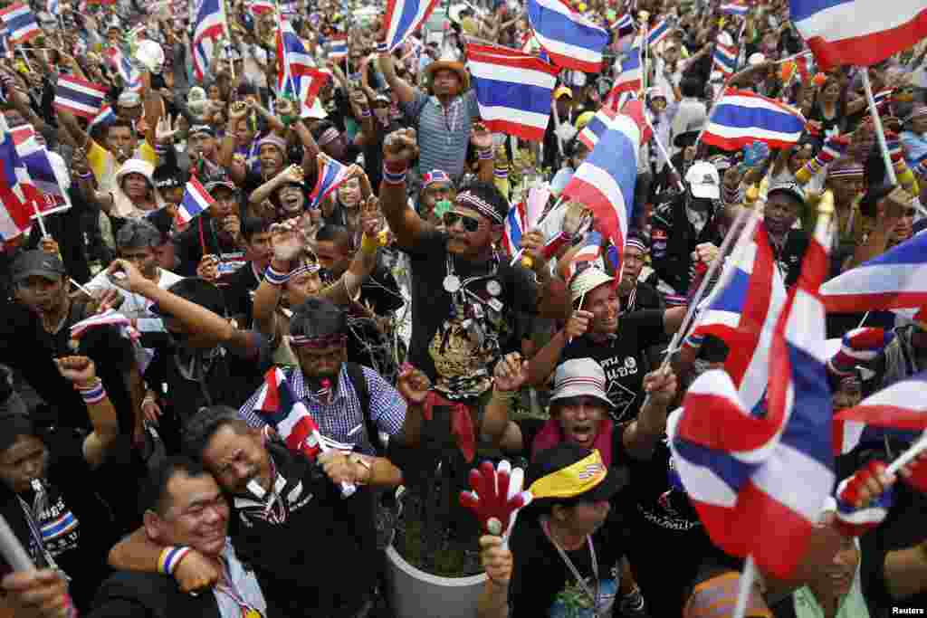 Anti-government protesters wave flags and blow whistles as one of their leaders addresses them at the Finance Ministry in Bangkok, Nov. 26, 2013. 