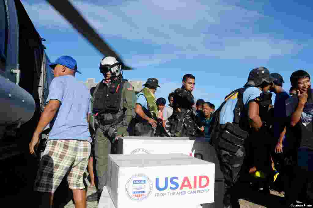 A U.S. Naval Air Crewman assists Philippine citizens in distributing relief supplies in support of Operation Damayan. (U.S. Navy)