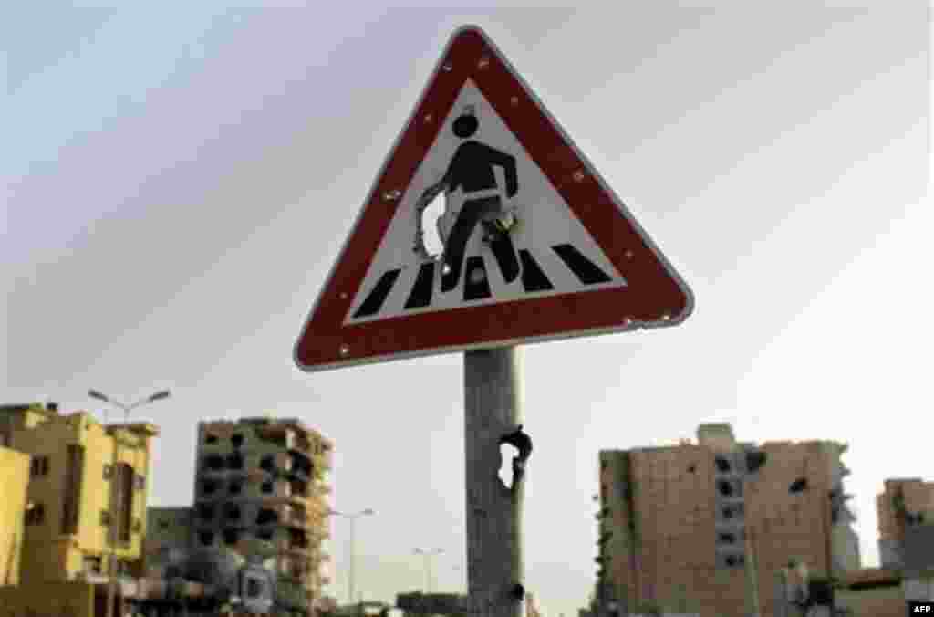 A foot crossing road sign with holes seen at Tripoli street in Misrata, Libya, Friday, Sept. 2, 2011. (AP Photo/Sergey Ponomarev)