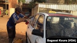 Un chauffeur de taxi lave son véhicule dans une rue de Niamey, le 16 mars, 2016. (VOA/Bagassi Koura)
