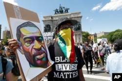 A man wears a Guyanese flag as his face protection as he listens to speakers during a Caribbean-led Black Lives Matter rally at Brooklyn's Grand Army Plaza, June 14, 2020, in New York.