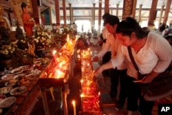 FILE - Local residents light candles during a ceremony to celebrate Pchum Ben, or Ancestors' Day at Krang Thnung Buddhist pagoda on the outskirts of Phnom Penh, Cambodia, Monday, Sept. 28, 2015.