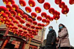 Warga Beijing berjalan dengan mengenakan masker di bawah lampion merah yang tergantung di sepanjang gang dekat Danau Houhai dalam perayaan Tahun Baru Imlek di Beijing, di tengah pandemi COVID-19, Kamis, 11 Februari 2021.