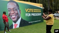 FILE - A man has his picture taken in front of an election campaign poster of Zimbabwe President Emmerson Mnangagwa portrait, in Harare, May, 4, 2018.