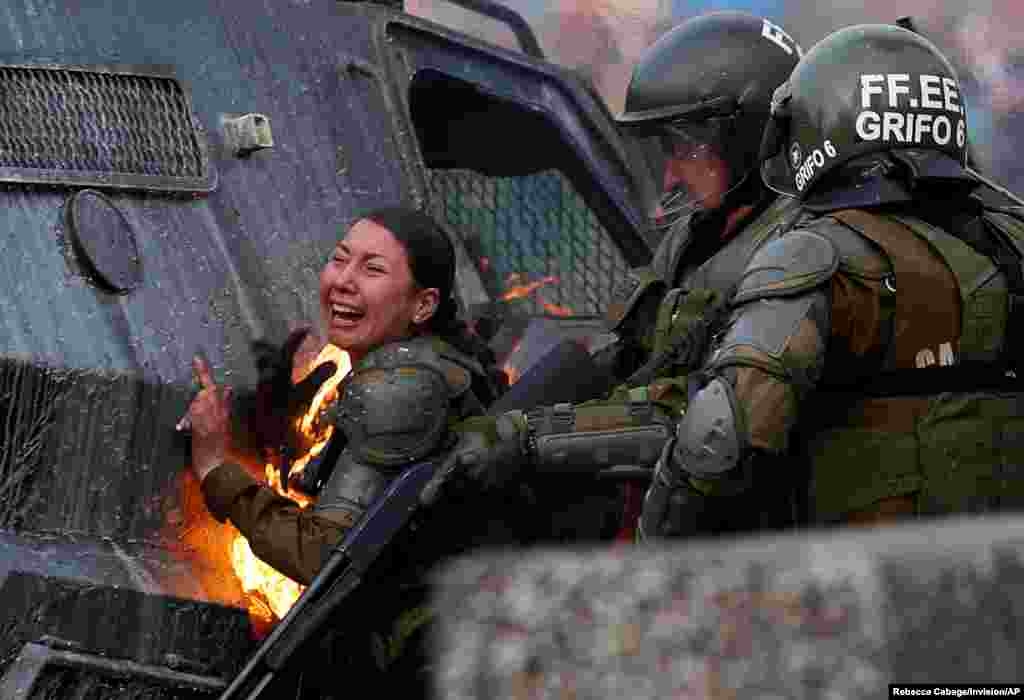 A riot police officer reacts after being hit with a gasoline bomb thrown by protesters during an anti-government protest in Santiago, Chile, November 4, 2019.