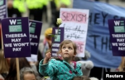 A girl holds a rose as protesters take part in the Women's March calling for equality, justice and an end to austerity in London, Jan. 19, 2019.