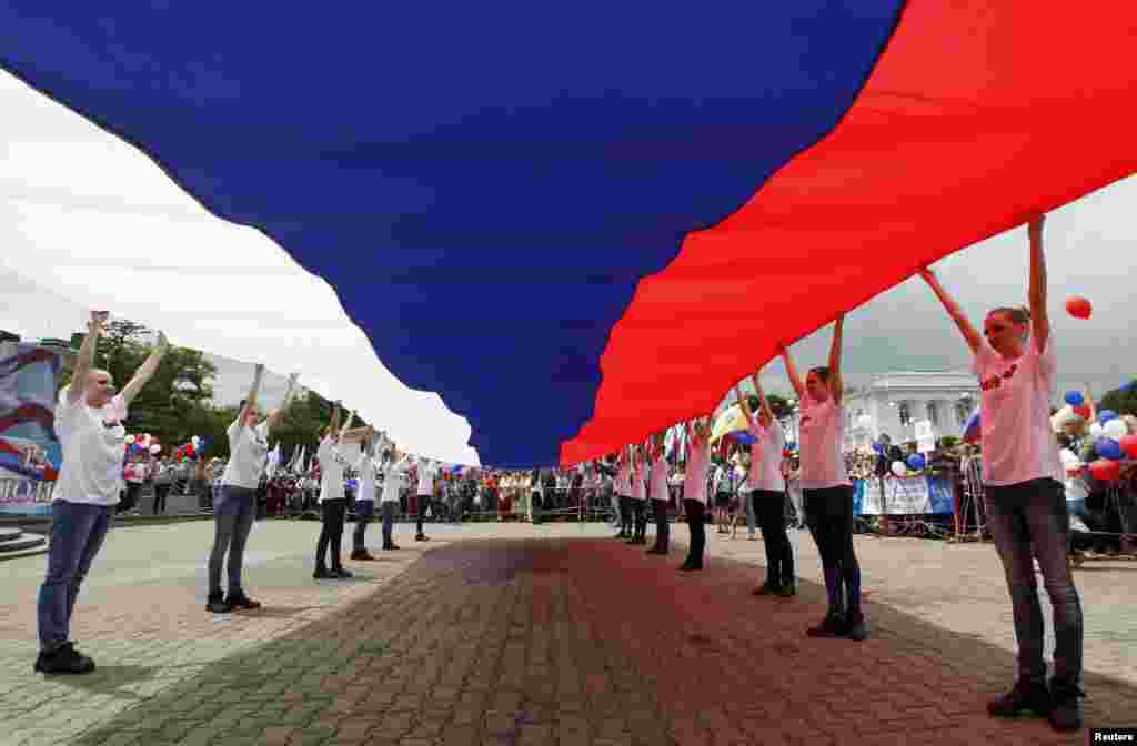 Sekelompok anak muda berbaris membentangkan bendera nasional Rusia dalam perayaan Hari Rusia di Stavropol, sebuah kota di bagian selatan Rusia.