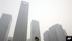 A woman walks past high rise buildings shrouded with hazy skyline in Beijing, China, 09 Oct 2010