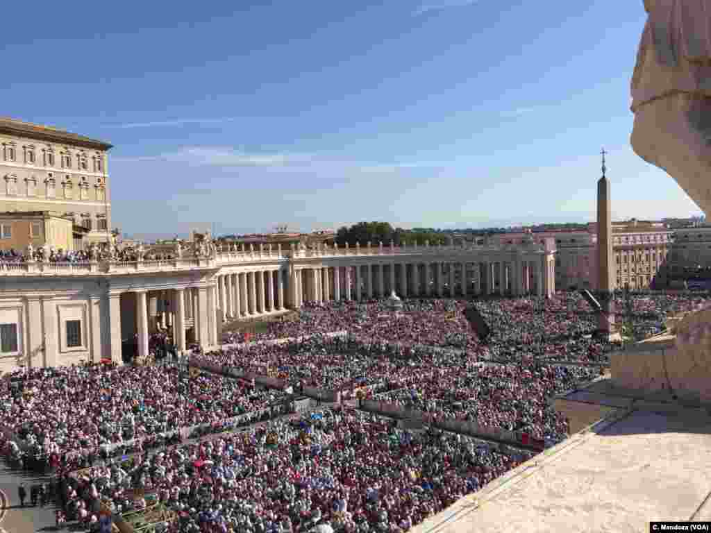 Multidão de fiéis ouvem a missa do Papa Francisco na Praça de São Pedro.