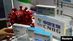 Kandidat za vakcinu Koneske nacionalne biotek grupe (CNBG), državne farmaceutske kompanije Sinofarm, izložena na Kineskom međunarodnom sajmu trgovine pored makete koronavirusa u Pekingu, 4, septembra 2020. (Foto: Rojters,Tingšu Vang)