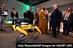Saudi Crown Prince Mohammed bin Salman visits a demonstration of technology, including a robotic "SpotMini" dog presented by Boston Dynamics CEO Marc Raibert, during a visit to Massachusetts Institute of Technology on Saturday, March 24, 2018.