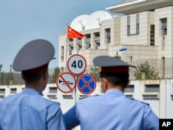 FILE - Kyrgyz police officers look at the Chinese Embassy after a suicide bombing in Bishkek, Kyrgyzstan, Aug. 30, 2016. In the past two years, militants belonging to the Uighur ethnic group native to the vast Xinjiang region in western China have shown signs of becoming a force in Islamic extremism globally.