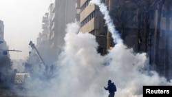 A protester throws a tear gas canister back at riot police in Cairo, November 25, 2012.