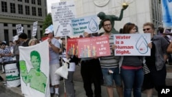 FILE - People stand outside Detroit City Hall, protesting thousands of residential water-service shutoffs by Detroit's water department, during a rally in Detroit, Thursday, July 24, 2014.