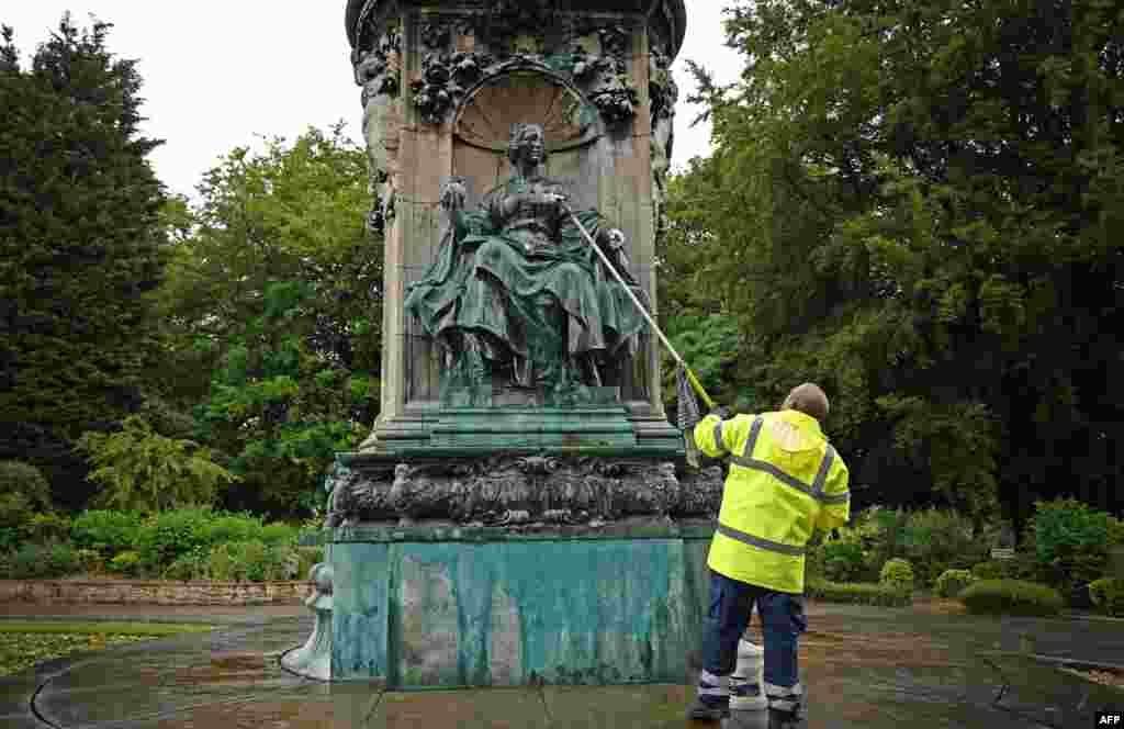 Council workers clean remove paint from a statue of Britain&#39;s Queen Victoria in Woodhouse Moor Park in Leeds, northern England.