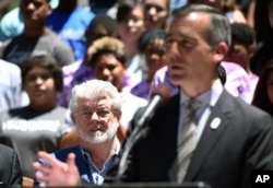 Filmmaker George Lucas, left, listens to remarks by Los Angeles Mayor Eric Garcetti at a news conference outside Los Angeles City Hall, June 27, 2017.