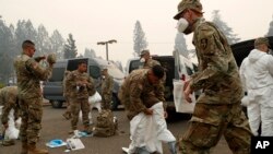 Members of the California Army National Guard don protective suits in preparation to search for human remains at the Camp Fire, Nov. 14, 2018, in Paradise, Calif. 