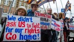 FILE - Protesters holding anti-American signs are seen gathered in front of the U.S. Embassy at a rally against what they see as American mingling in Russia's internal affairs, in Moscow, Russia, March 7, 2015.