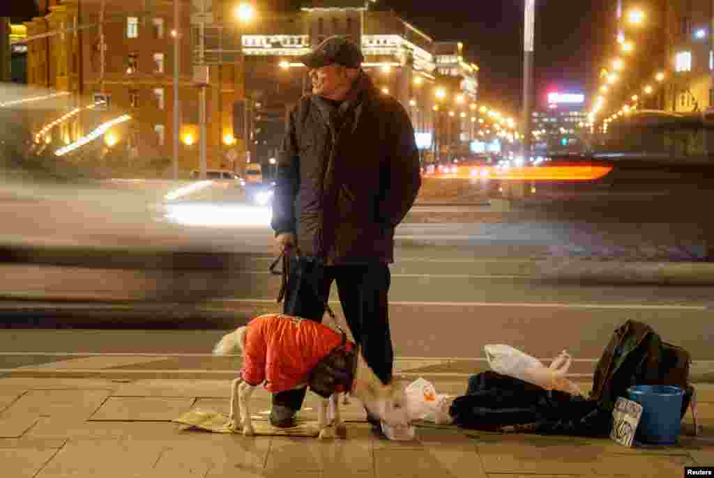 A man with a goat begs for money near a road in the center of Moscow, Russia, Nov. 15, 2018.