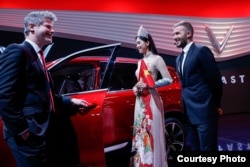 (L-R) Director of Design of VinFast Dave Lyon, Miss Vietnam 2018 Tran Tieu Vy and David Beckham attend VinFast launch at the Paris Motor Show at Parc des Expositions, Porte de Versailles on October 2, 2018, France.