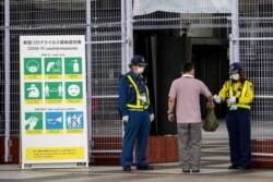 Petugas keamanan memeriksa akreditasi dan suhu tubuh seorang pria yang memasuki Tokyo Big Sight, situs International Broadcast Center (IBC) dan Main Press Center (MPC) Tokyo 2020, 9 Juli 2021. (Foto: AFP)