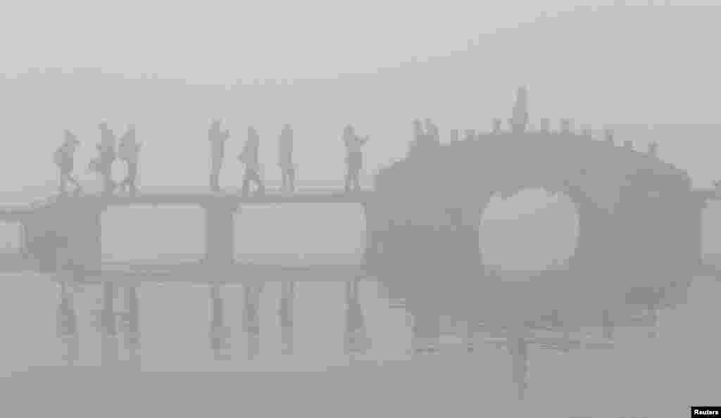 Visitors walk on a bridge as they visits the West Lake amid thick fog and heavy smog in Hangzhou, Zhejiang province, China.