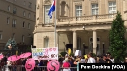 Quốc kỳ Cuba được kéo lên tại Đại sứ quán mới mở lại ở thủ đô Washington trong lúc những người biểu tình cầm áp phích và khẩu hiệu chống đối, ngày 20/7/2015 (Ảnh: Pam Dockins/VOA).