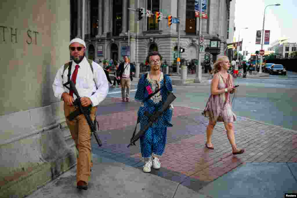 A woman walks past Micah Naziri and Jaimes Campbell, advocates for open carry, as they patrol the streets of Cleveland with their assault weapons during the Republican National Convention in Ohio, July 19, 2016.