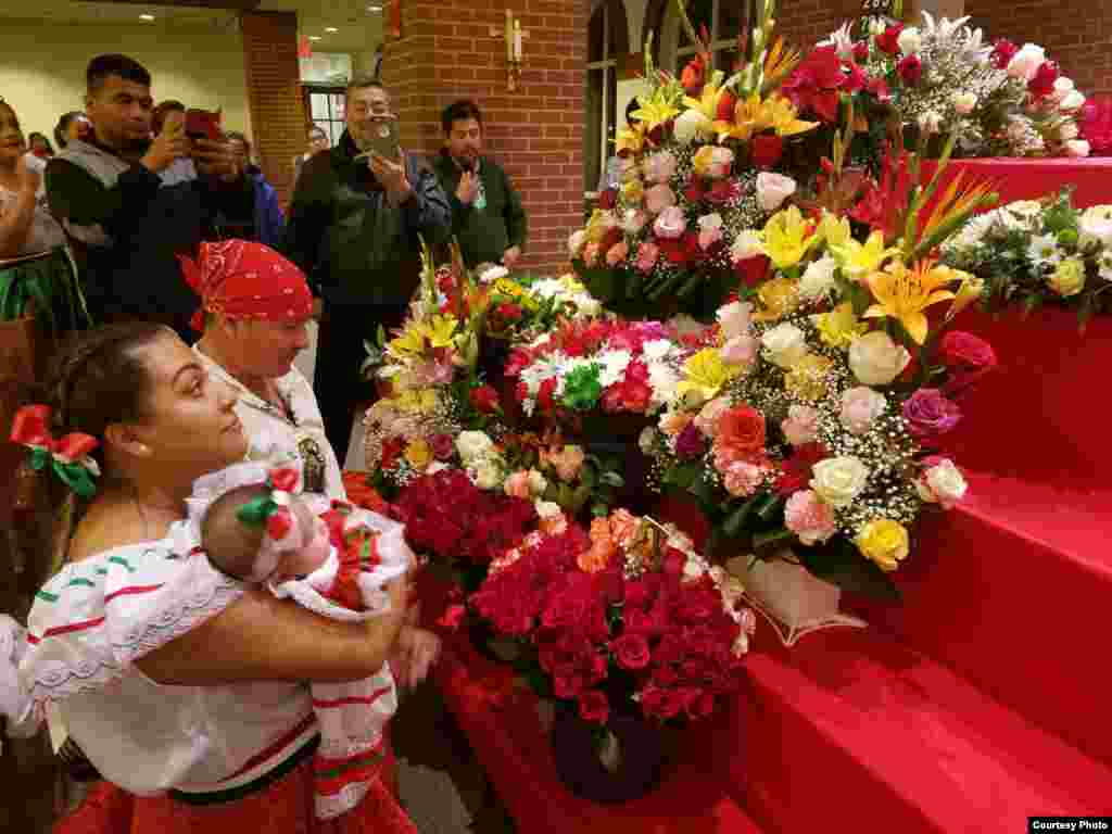 Una familia se arrodilla en frente del altar de la Virgen de Guadalupe, lleno de flores, para orar, el miércoles 12 de diciembre de 2018. Foto: Mitzi Macias- VOA
