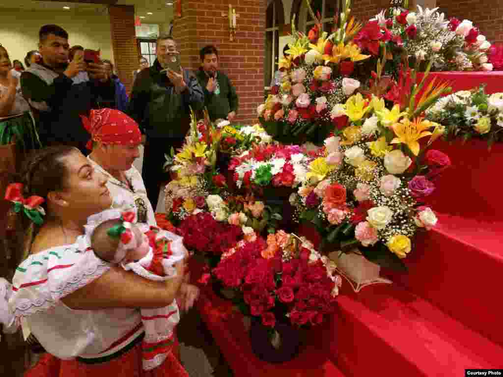 Una familia se arrodilla en frente del altar de la Virgen de Guadalupe, lleno de flores, para orar, el miércoles 12 de diciembre de 2018.&nbsp; Foto: Mitzi Macias- VOA