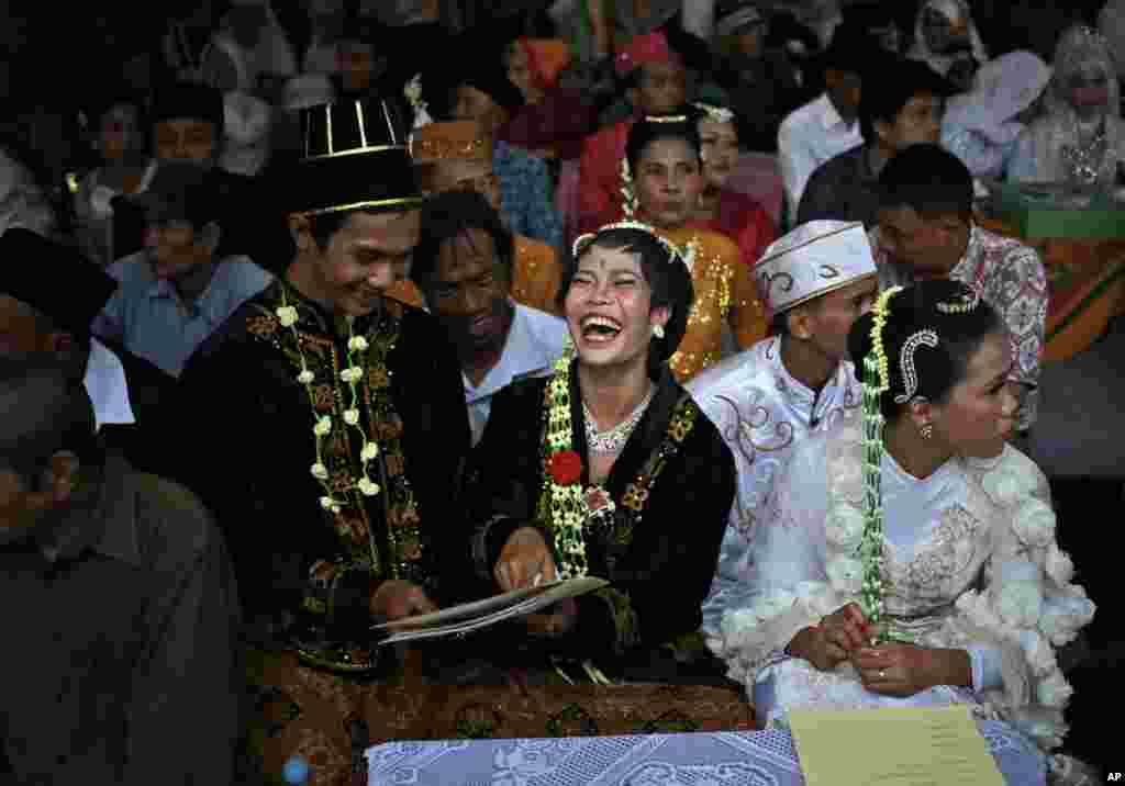 Pasangan pengantin tersenyum bahagia setelah memperoleh surat pernikahan pada acara pernikahan massal di Jakarta. Pemda DKI membantu kalangan keluarga tak mampu dengan menyelenggarakan acara nikah massal bagi mereka.