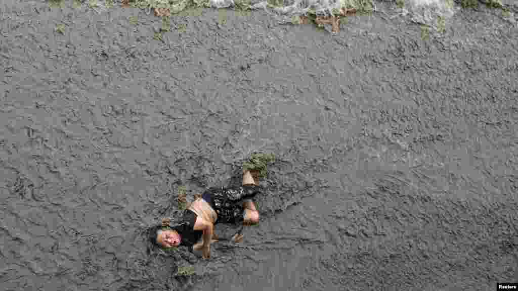 Seorang pria terjatuh dari jembatan, saat ombak besar menerpanya di sungai Qiantang di kota Hangzhou, Zhejiang, China.