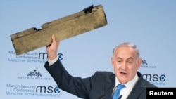 Israeli Prime Minister Benjamin Netanyahu holds up a remnant of what he said was a piece of Iranian drone which was shot down in Israeli airspace during his speech at the Munich Security Conference, Germany, Feb. 18, 2018. 