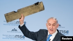 Israeli Prime Minister Benjamin Netanyahu holds up a remnant of what he said was a piece of Iranian drone which was shot down in Israeli airspace during his speech at the Munich Security Conference, Germany, Feb. 18, 2018. 