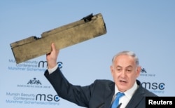 Israeli Prime Minister Benjamin Netanyahu holds up a remnant of what he said was a piece of Iranian drone which was shot down in Israeli airspace during his speech at the Munich Security Conference, Germany, Feb. 18, 2018.