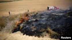 Israeli firefighters attempt to extinguish fire burning scrubland in area where Palestinians have been causing blazes by flying kites and balloons loaded with flammable materials, July 20m 2018.