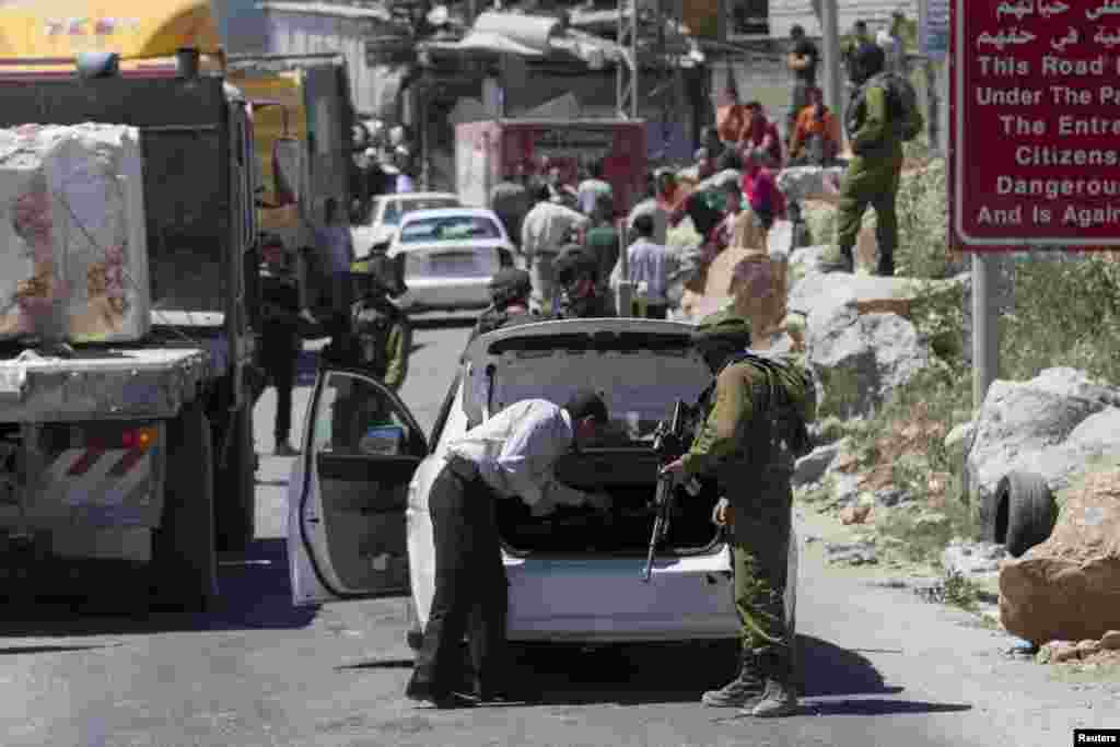An Israeli soldier searches a Palestinian vehicle at a checkpoint near the West Bank City of Hebron, June 15, 2014. 