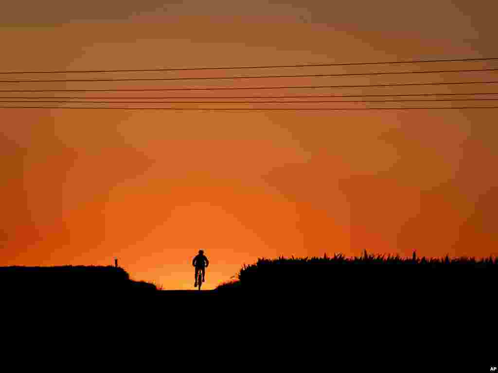 A man rides his bike up a hill just before the sun rises in Frankfurt, Germany.