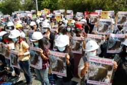 Lulusan Universitas Mandalay memegang poster bergambar Mya Thwet Thwet Khine, perempuan 19 tahun yang tertembak aparat saat berunjuk rasa pada 9 Februari di Naypyitaw, dalam aksi protes anti-kudeta di Mandalay, Myanmar, 14 Februari 2021.