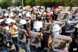 Lulusan Universitas Mandalay memegang poster bergambar Mya Thwet Thwet Khine, perempuan 19 tahun yang tertembak aparat saat berunjuk rasa pada 9 Februari di Naypyitaw, dalam aksi protes anti-kudeta di Mandalay, Myanmar, 14 Februari 2021.