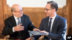 French foreign minister Jean-Yves Le Drian, left, and his German counterpart Heiko Maas, exchange documents at Villa Borsig in Berlin, May 7, 2018. 