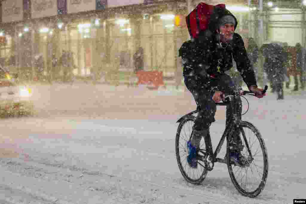 ایک شخص برفباری کے دوران سائیکل چلا رہا ہے۔